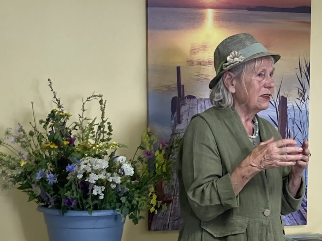 Dorisa Winkenbach steht neben einem Blumentopf voller Kräuter, während sie den Vortrag hält.