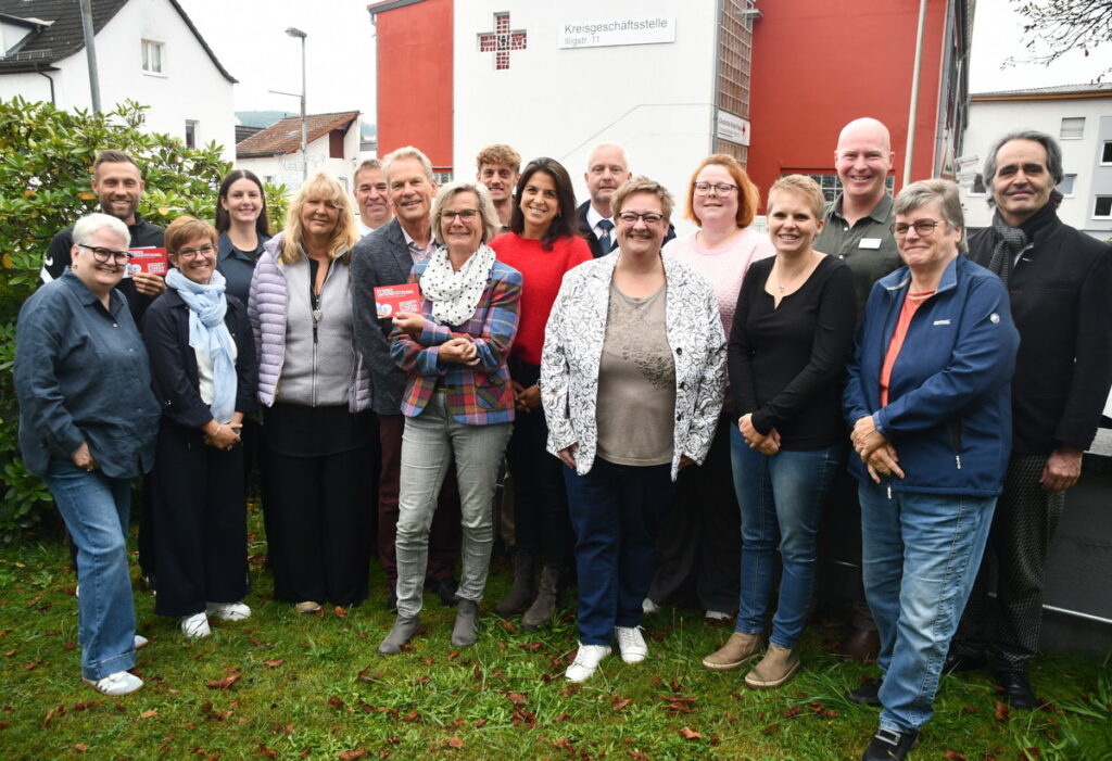 Eine Gruppe von Leuten steht vor einem Rot-Kreuz-Gebäude.