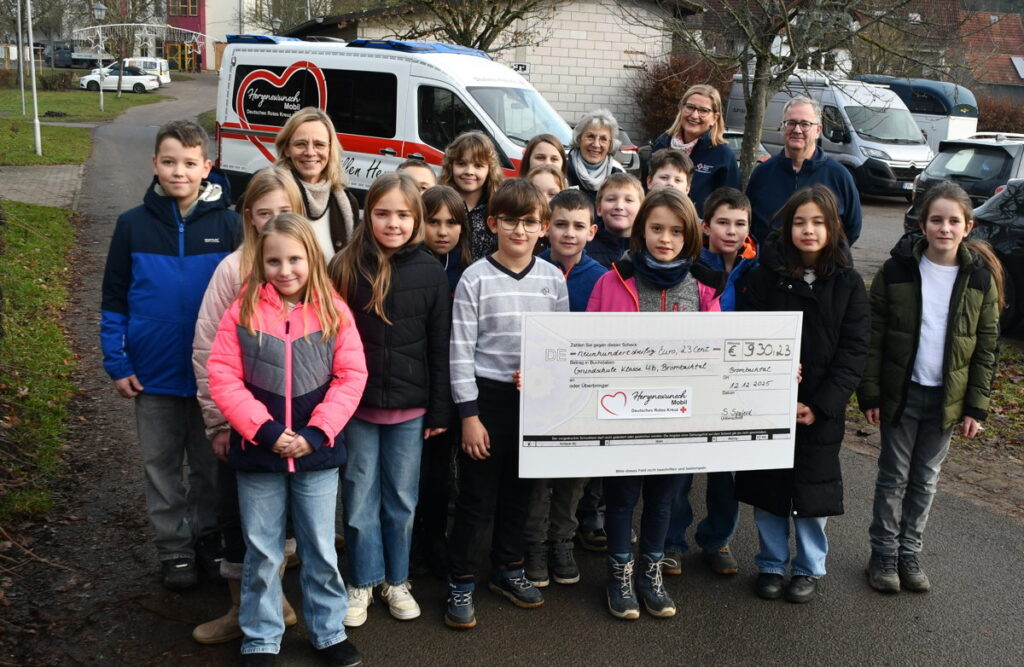 Das Bild zeigt die fleißige „Erdmännchen-Klasse“ mit Lehrerin Sylvia Sperfeld, Ideengeberin Tara Paul (vorne mit symbolischem Scheck) sowie hintere Reihe von rechts Helfer Dieter Sedlacek, Organisatorin Kerstin Truber und Palliativ-Ärztin Dr. Agnes Reifschneider vom Team des DRK-Herzenswunsch-Mobils. (Foto: DRK)
